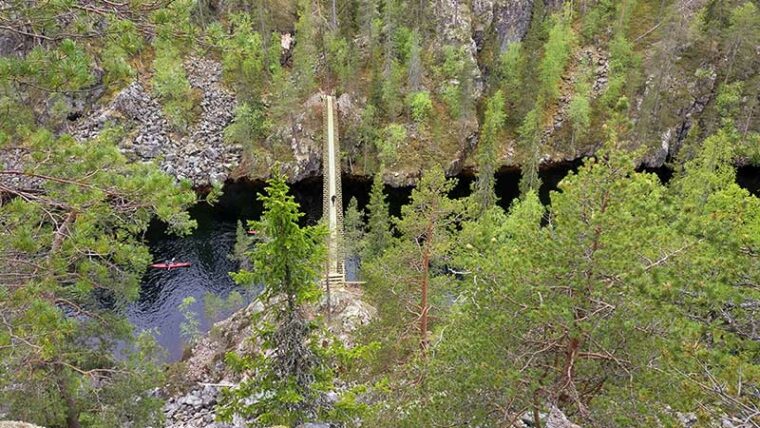 Ilmakuvassa riippusilta, joka ylittää rotkossa virtaavan joen.