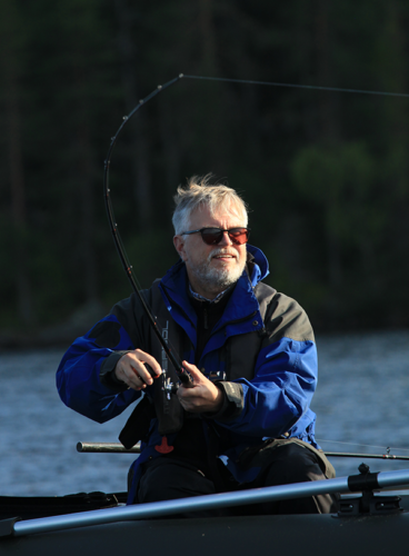 En man sitter i en båt och fiskar.