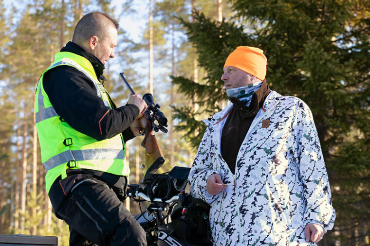 Erätarkastaja tarkastaa metsästäjän asetta ja metsästyslupaa.