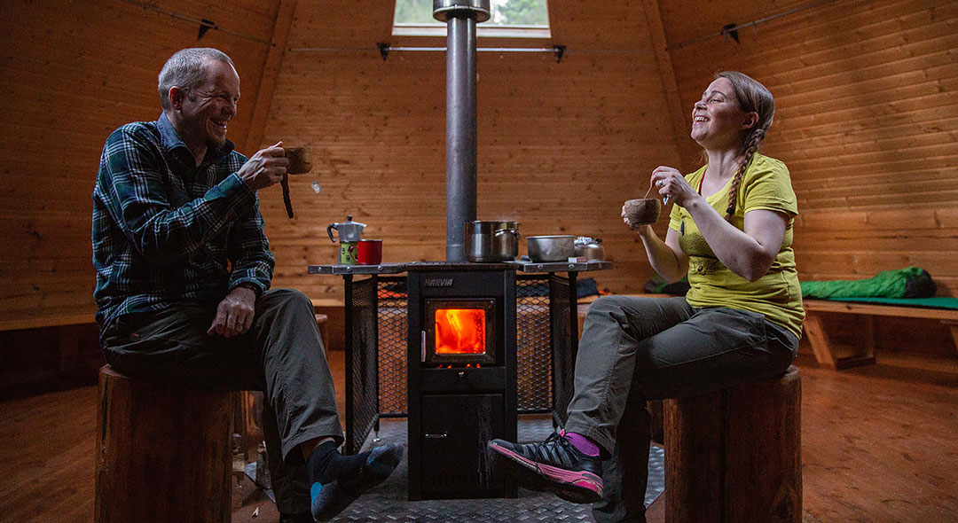 Two people are having a snack inside a traditional wooden building.