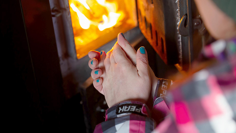 Close-up of hands in front of fireplace.