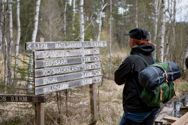 Retkeilijä katsoo reitin varrella olevaa opasviittaa.